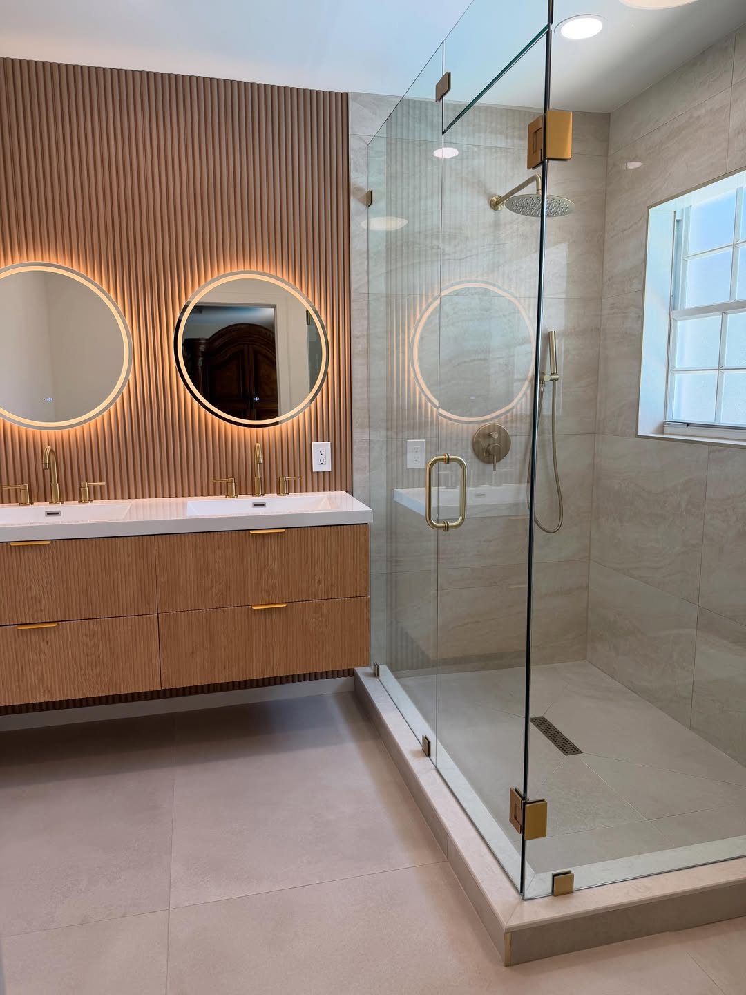 Fluted wood vanity with round backlit mirrors