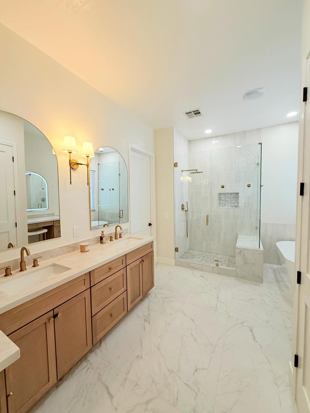 Bright master suite with arched mirrors and walk-in shower